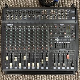 Černý mixovací pult s nápisy YAMAHA a EMX 2000. Zařízení obsahuje početné vstupní kanály s potenciometry, přepínači a posuvníky. V pravé části je umí…