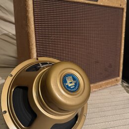 Na fotografii je kytarový zesilovač v béžovém potahu s hnědou mřížkou a zlatý reproduktor. Na horní hraně zesilovače je nápis Fender Harvard. Reprodu…