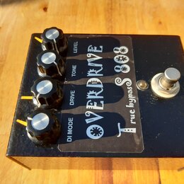 Černý kytarový efekt s nápisem OVERDRIVE TS 808 a doplňkem true bypass. Na horní straně jsou čtyři černé otočné knoflíky s kovovými vršky a popisky L…