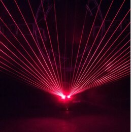 Fotografie zachycuje červený laserový efekt v temném prostoru. Z jednoho zdroje vychází vějíř rovných červených paprsků směřujících do horní části sn…