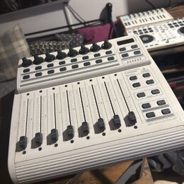 Bílý USB MIDI kontrolér s osmi posuvníky a řadou otočných knoflíků v horní části. Na pravé straně jsou umístěna tlačítka a nápisy B-CONTROL, MIDI FAD…