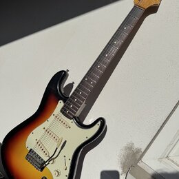 Elektrická kytara s telym v provedení sunburst a bílým pickguardem. Na hlavě hředu je viditelné logo Fender. Nástroj má tři snímače, pětistupňový pře…