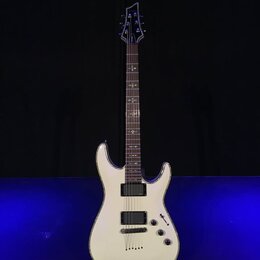 Bílá elektrická kytara s dvojstupňovitým tělem a tmavým hmatníkem. Nástroj má dva humbuckery, jeden ovládací knoflík hlasitosti a jeden tón. Na hlavě…