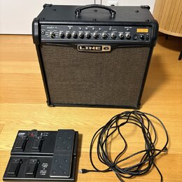 Černý kytarový kombo zesilovač s nápisem SPIDER IV 75 a logem LINE 6. Přední panel obsahuje ovládací knofíky, přepínače a zelenou kontrolku. Před zes…