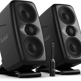 Dva černé studiové monitory značky iLoud, každý s dvěma membránami krytými kovovou mřížkou. Reproduktory stojí na černých podstavkách a v popředí je…