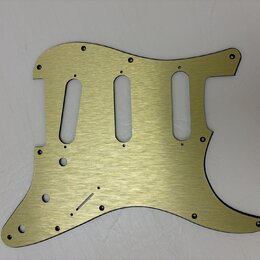 Zlatý kovový pickguard pro elektrickou kytaru s broušeným povrchem. Má tři oválné výřezy pro snímače a několik malých otvorů na šrouby. Na povrchu ne…