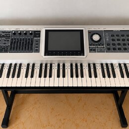 Stříbrný digitální klavír s černými klávesami a ovládacím panelem. Na levé straně je nápis Roland a na pravé straně model Fantom G7. V horní části se…