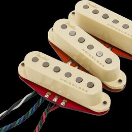 Tři kytarové snímače v krémovém provedení s kovovými póly. Každý snímač má nápisy Fender a NOISELESS. Snímače jsou umístěny na červených a oranžových…