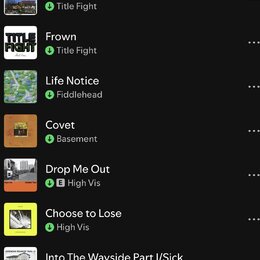 Snímek zachicuje seznam skladeb v digitální aplikaci na černém pozadí. Jsou zde uvedeny názvy písní a interpretů: Shed (Title Fight), Frown (Title Fi…