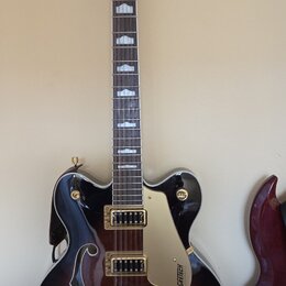 Polodublová elektrická kytara s tmavě hnědým gradientním povrchem a f-otvory. Na hlavě i na plechovce je viditelné logo GRETSCH, hриф má bílé vložky.…