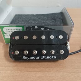 Černý humbucker s dvěma řadami magnetických pólů. Na spodní části je bílý nápis Seymour Duncan. Povrch plastového krytu vykazuje drobné škrábance a z…