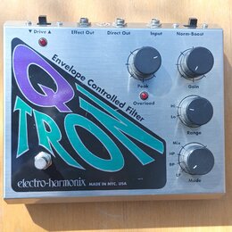Kytarový efekt v kovovém šasi s nápisem Q TRON a textem Envelope Controlled Filter. Na přední straně jsou čtyři ovládací knoflíky s popisky Peak, Gai…