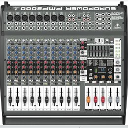 Šedý mixážní pult s černými ovládacími prvky. V horní části je nápis EUROPOWER PMP3000 a logo BEHRINGER. Zařízení obsahuje několik vstupních kanálů s…