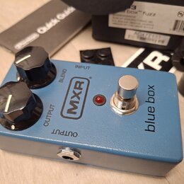 Modrý kytarový efekt s nápisy MXR a blue box. Na horní straně jsou dva černé otočné knoflíky s popisky BLEND a OUTPUT, červená kontrolka a kovový spí…