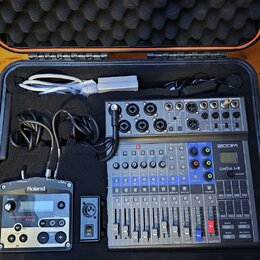 V černém přepravním kufru s pěnovou výplní se nachází digitální mixáž ZOOM LiveTrak L-8, modul Roland TR-505 a bílý napájecí adaptér s kabelem. Na mi…