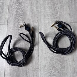 Dvě černé pletené audio kabelové spoje s úhlovým a rovným konektorem. Na obou kabelech je u konektorů viditelné modré logo s nápisem "Savage". Kabely…