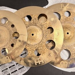 Tři mosazné činely s otvory v ploše, značky Byzance. Na každém je vidět nápis Byzance a v dolní části logo MEINL. Povrchy jsou nerovnoměrně zbarvené…
