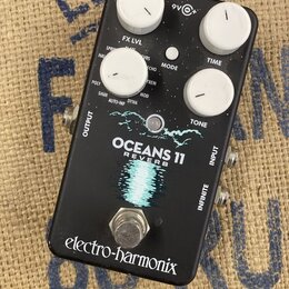Černý efektový pedál s bílými ovládacími knoflíky. Na spodní části je nápis electro-harmonix a uprostřed název modelu OCEANS 11 REVERB s grafickým mo…