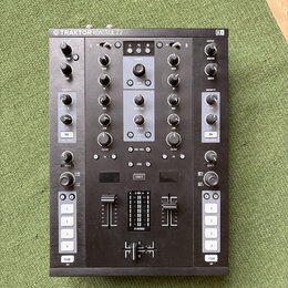 Černý DJ kontroler s nápisem TRAKTOR KONTROL Z2 a logem NI v pravém horním rohu. Zařízení obsahuje dva kanály s knoflíky Gain, Mid a Low, faderem hla…