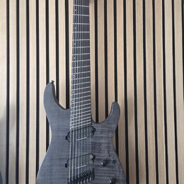 Šedá elektrická kytara s tmavým hnedým povrchem a viditelnou strukturou dřeva. Na hlavě je bílý nápis LTD Deluxe. Nástroj má dva humbuckery, jeden ov…