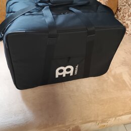 Černá transportní taška z textiledního materiálu s rukojetí a ramenním popruhem. Na přední straně je bílé logo ve tvaru stylizovaného písmena B a ved…