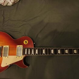 Elektrická kytara s tvarem singlecut a povrchovou úpravou v červeně-žlutém gradientu (sunburst). Má dva humbuckery, bílý pickguard a čtyři ovládací k…