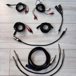Sada různých audio kabelů v černé barvě rozložená na světlé podložce. Jsou zde kabely s konektory RCA (červené a bílé), jack 3,5 mm, 6,35 mm oraz XLR…