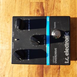 Černý kytarový efekt s nápisy t.c. electronic a VINTAGE OVERDRIVE. Na horní straně jsou tři černé otočné knoflíky s popisky output level, color filte…
