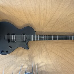 Černá elektrická kytara s matným povrchem a dvěma humbuckery. Na hlavě hředu je bílý nápis "Yamaha". Hриф obsahuje jeden viditelný znak vtíraný do hm…