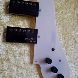 Bílá plastová plocha s dvěma černými humbuckery. Na spodním snímači je bílý nápis LAFAYETTE a pod ním číslo 99-4583. V pravé části jsou tři černé oto…