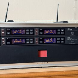 Hliníkový přepravní kufr obsahuje dva černé bezdrátové přijímače značky Letone, model free solo Twin DR 590 MHz. Každý přijímač má digitální displej…