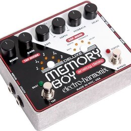 Bílý efekt pedál s červeným okrajem a kovovým šasi. Na horní straně je nápis DELUXE MEMORY BOY analog delay electro-harmonix a text MADE IN NYC, USA.…