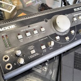 Šedý monitorovací kontrolér značky MACKIE s nápisem BIG KNOB STUDIO COMMAND SYSTEM. Zařízení obsahuje velký centrální knofík VOLUME, sekci INPUT SOUR…