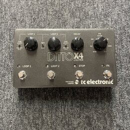 Šedý kytarový pedál s nápisem DITTO X4 LOOPER a logem tc electronic. Zařízení má čtyři stoupací spínače označené jako LOOP 1, LOOP 2, STOP a FX. Na h…