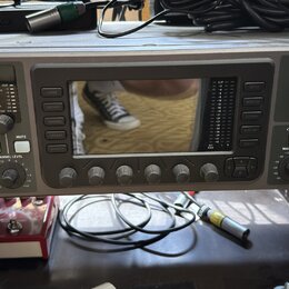 Šedý rackový digitální mixér s nápisem behringer X32 RACK POWERED BY MIDAS. Zařízení má centrální displej, několik ovládacích tlačítek a pět otočných…