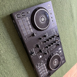 Černý DJ 컨트롤러 s dvěma jogovými koly a centrálním mixážním sekcí. Na přístroji jsou viditelné nápisy rekordbox, Pioneer DJ a model DDJ-400. Povrch je…