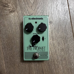 Světle zelený kytarový efekt s nápisem tc electronic a THE PROPHET DIGITAL DELAY. Na horní straně jsou dva černé otočné oválné knoflíky s popisky TIM…