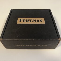 Černá papírová krabička s hnědým obdélníkovým polem, ve kterém je černý nápis FRIEDMAN. Na spodní hraně krabice je uveden web FRIEDMANAMPLIFICATION.C…