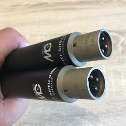 Dvě černé válcové součástky s kovovými konektory na koncích. Na tělech je bílé logo MG a nápisy GEFELL GMBH, MADE IN GERMANY. Na kovových částech je…