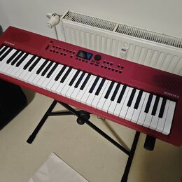 Červený digitální klavír značky Roland, model GO:KEYS 3. Nástroj je umístěn na černém skládacím stojanu. Povrch je v dobrém stavu bez viditelného opo…