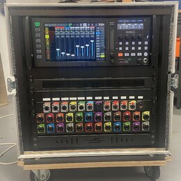 Digitální mixovací pult BEHRINGER WING umístěný v rackovém kufru s pěnovým vnitřkem. Pod mixem se nachází rozhraní s řadou barevných konektorů a nápi…