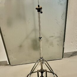 Stříbrný kovový stativ s teleskopickým ramenem a třínožkou. V dolní části se nachází plochý kovový pedal. Na stativu nejsou viditelné žádné značky an…