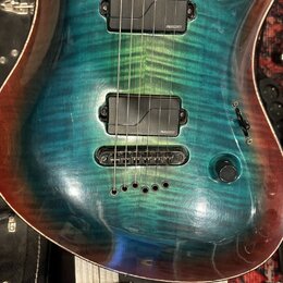 Elektrická kytara s modrozelým plamenovým javorovým topem a hnědými okraji. Nástroj má dva černé humbuckery, na kterých je viditelný nápis FISHMAN. K…