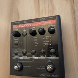 Černý efektový pedál s nápisy TC-HELICON a harmony G·XT. Zařízení má čtyři otočné ovladače (Input, Tone, FX, Harmony), přepínač Guitar s výběrem efek…