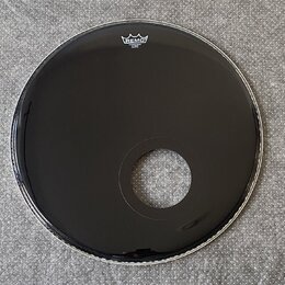 Černá bubnová blána s vyříznutým otvorem v dolní části. V horní části je bílé logo REMO a pod ním menší nečitelný nápis. Povrch je hladký a lesklý be…