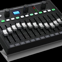 Černý mixovací pult značky behringer, model P24. Zařízení obsahuje 12 posuvníků s bílými knoflíky, řadu zelených tlačítek s čísly 1 až 12 a modrý dis…