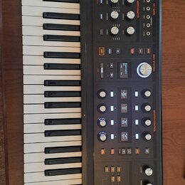 Černý syntetizátor s klaviaturaí. Na horním panelu je oranžové logo ASM Electric Music Company a nápis HYDRASYNTH. Přístroj obsahuje numeroustovací k…