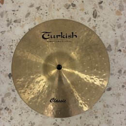 Kruhové činely z mosazného kovu s kovaným povrchem. Na horní části je černý nápis Turkish a pod ním menší text handmade cymbals from Turkey. Ve spodn…