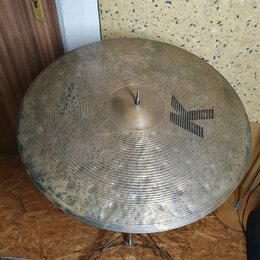 Zlatý činely s koncentrickými rýhami a viditelným opotřebením povrchu. Na ploše je černé logo ve tvaru velkého písmena K a nápis Custom Dry Ride. V d…