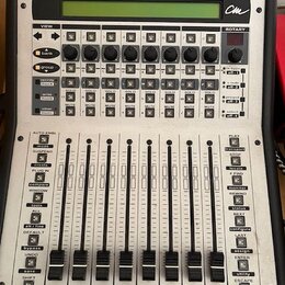 Stříbrný digitální mixovací kontroler s nápisem motor mix Digital Mixer Worksurface a logem cm. Zařízení obsahuje LCD displej, řadu otočných knoflíků…
